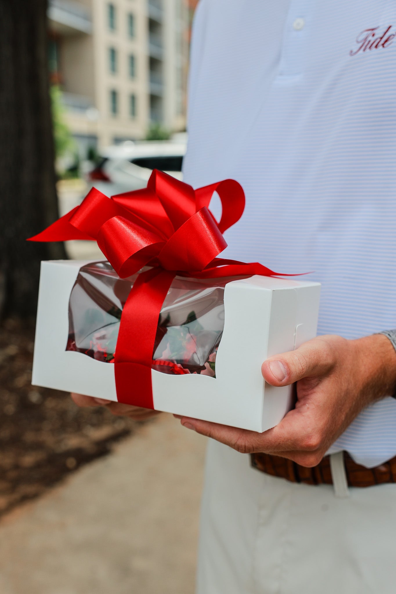 Person holding a wrapped delivery of chocolate covered strawberries in Tuscaloosa Alabama