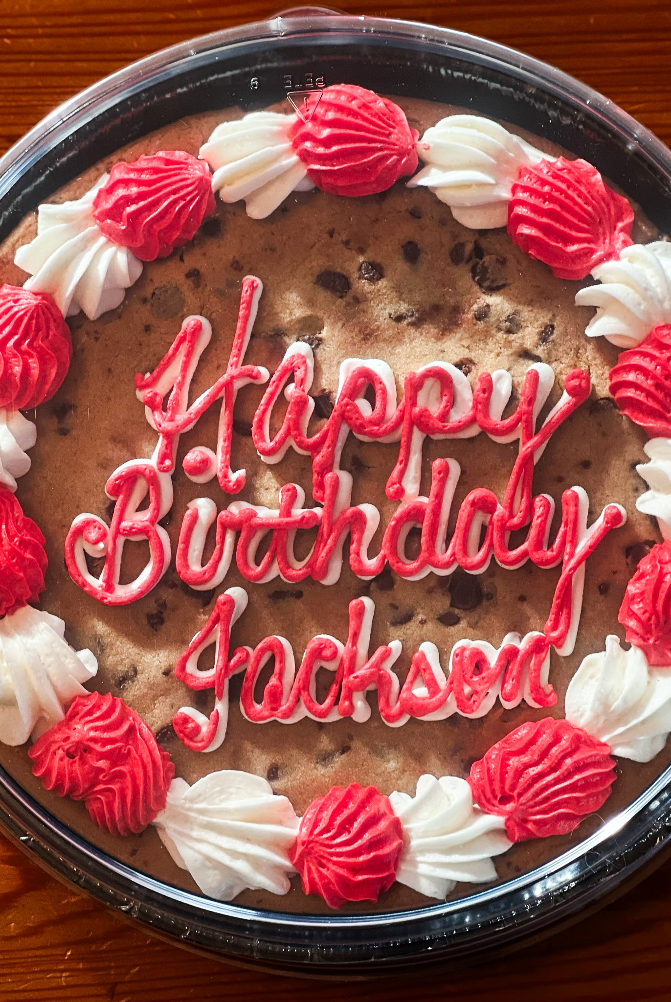 Cookie cake with red and white icing that says "happy birthday Jackson"