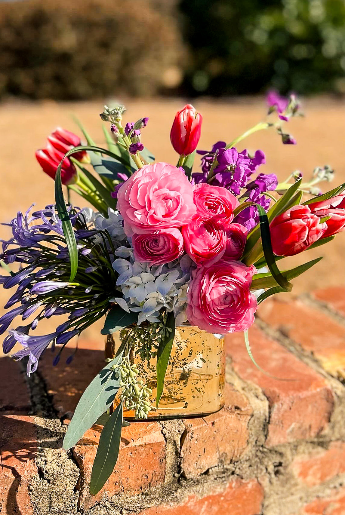 Pink and purple flower arrangement on a brick wall