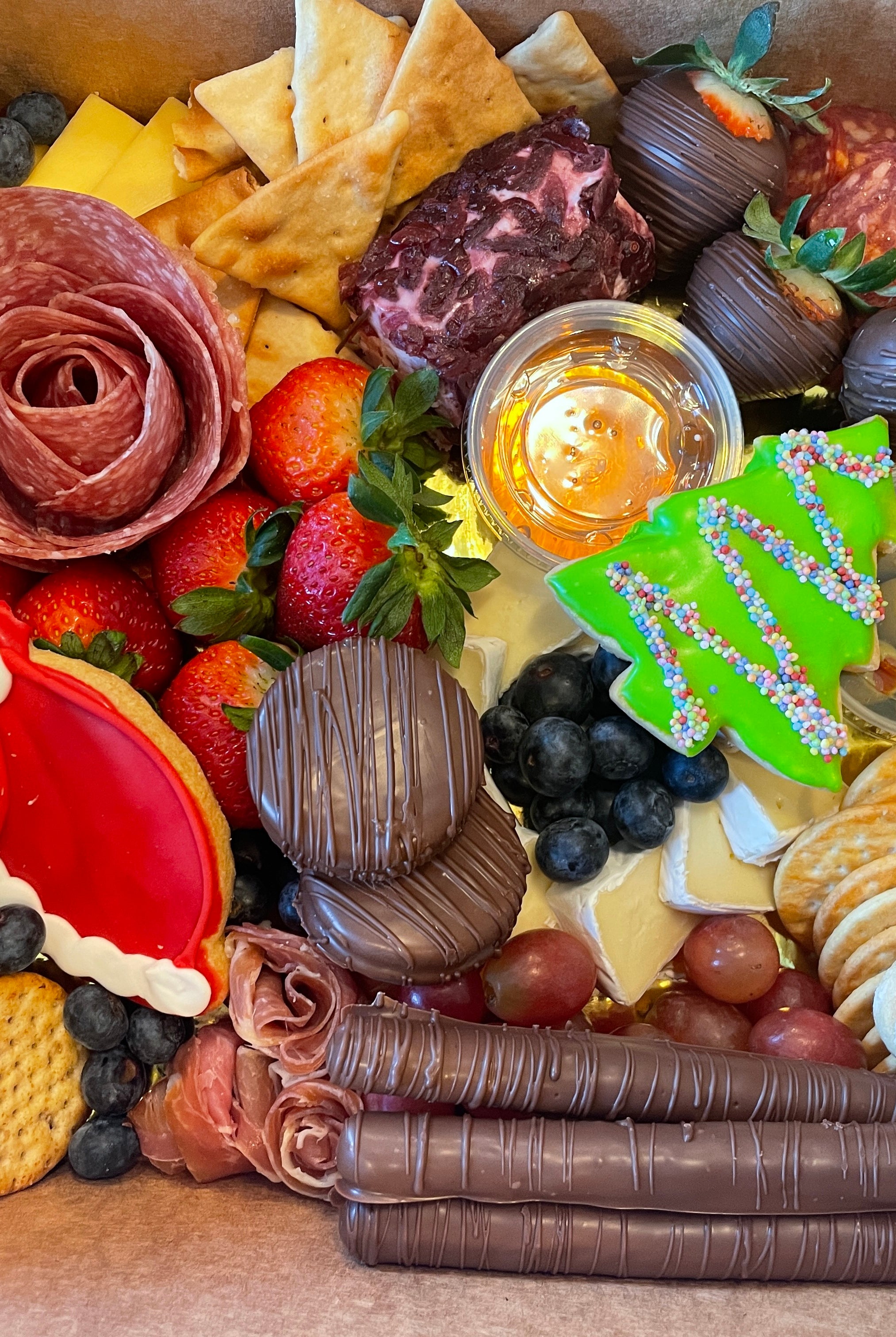 Christmas themed charcuterie board prepared for delivery in Tuscaloosa. It features cheese, fruits, Christmas cookies, meats and crackers.