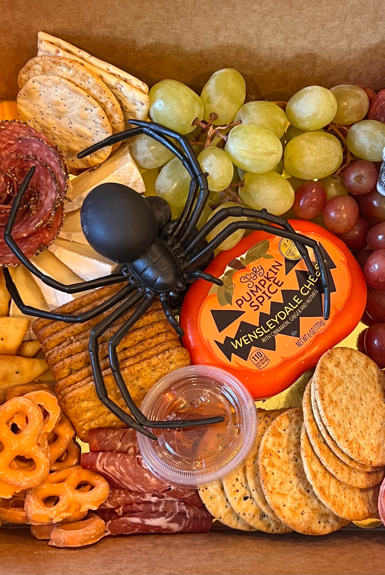 Halloween themed charcuterie board prepared for delivery in Tuscaloosa. It features crackers, cheeses, Halloween decor, meats and fruits.