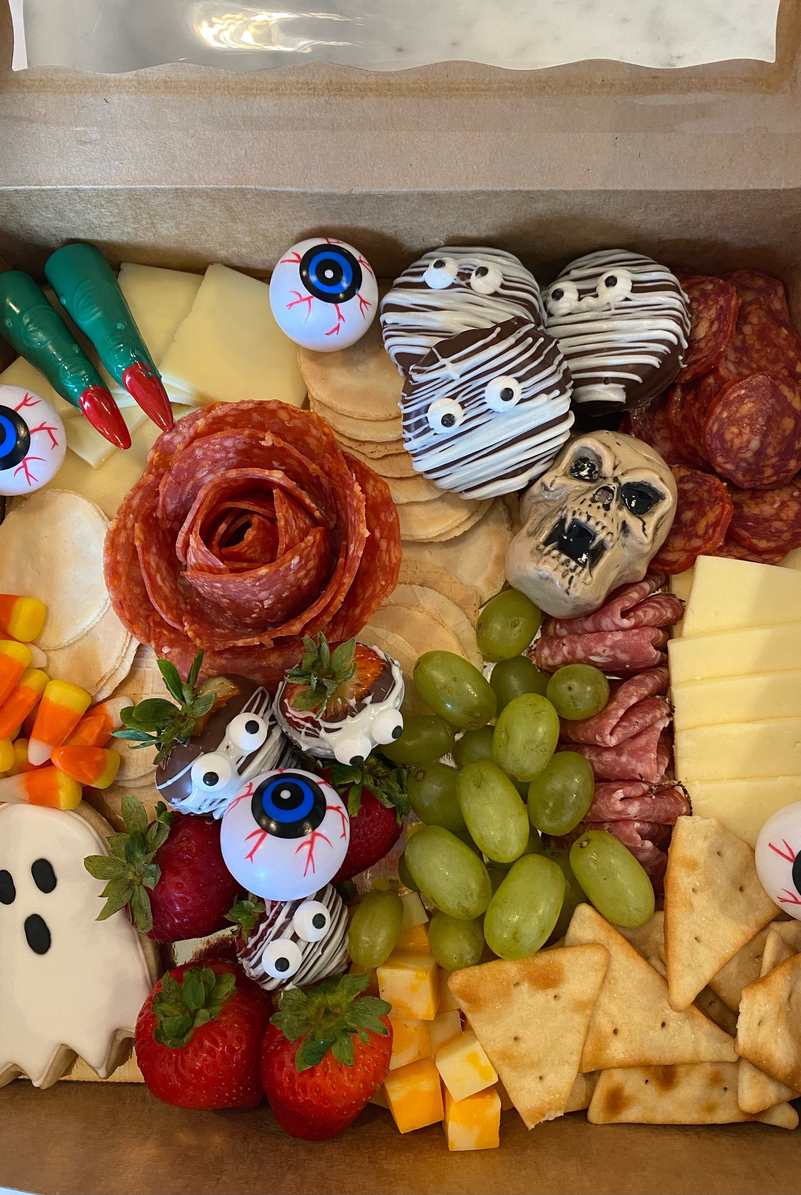 Halloween themed charcuterie board prepared for delivery in Tuscaloosa Alabama. It features crackers, meats, fruits, and candy corn and halloween treats and decor.