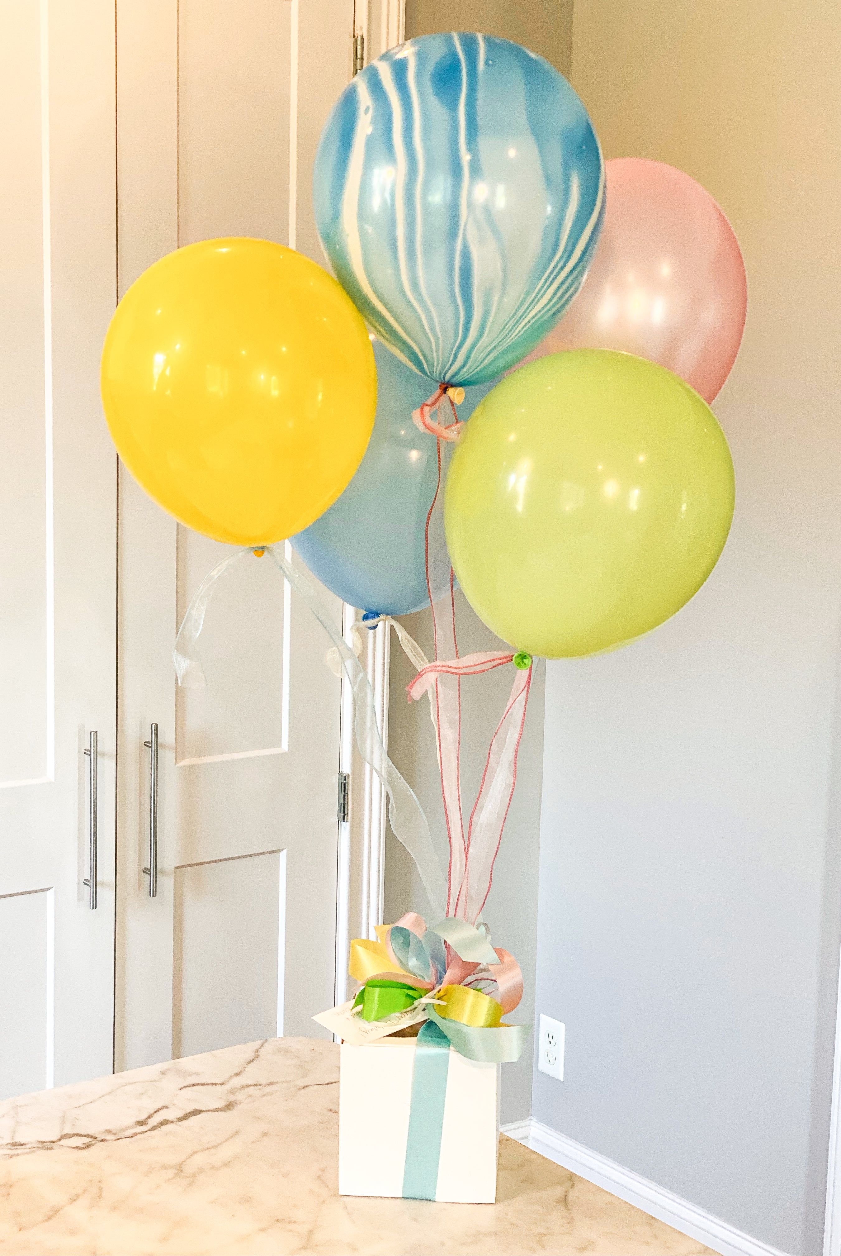 Various color balloon bundle tied to a gift box