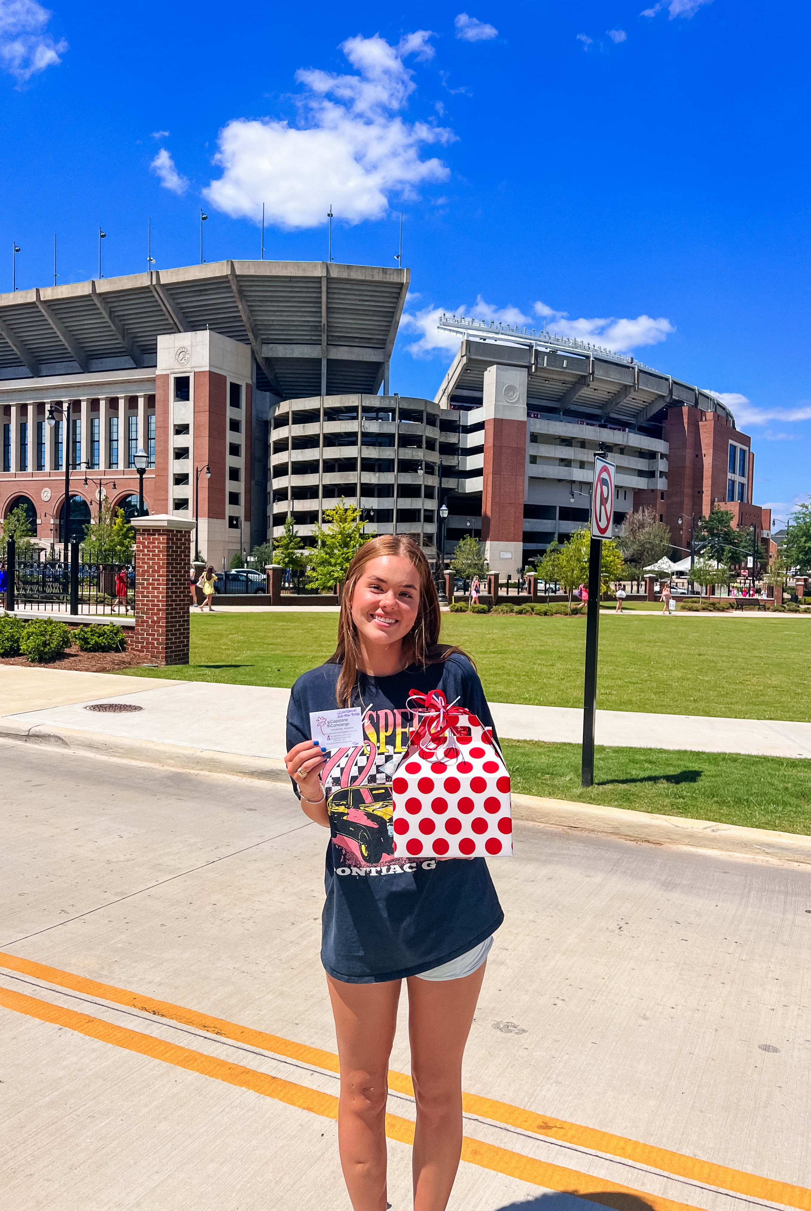 Girl holding red and white delivery outside of Bryant Denny stadium