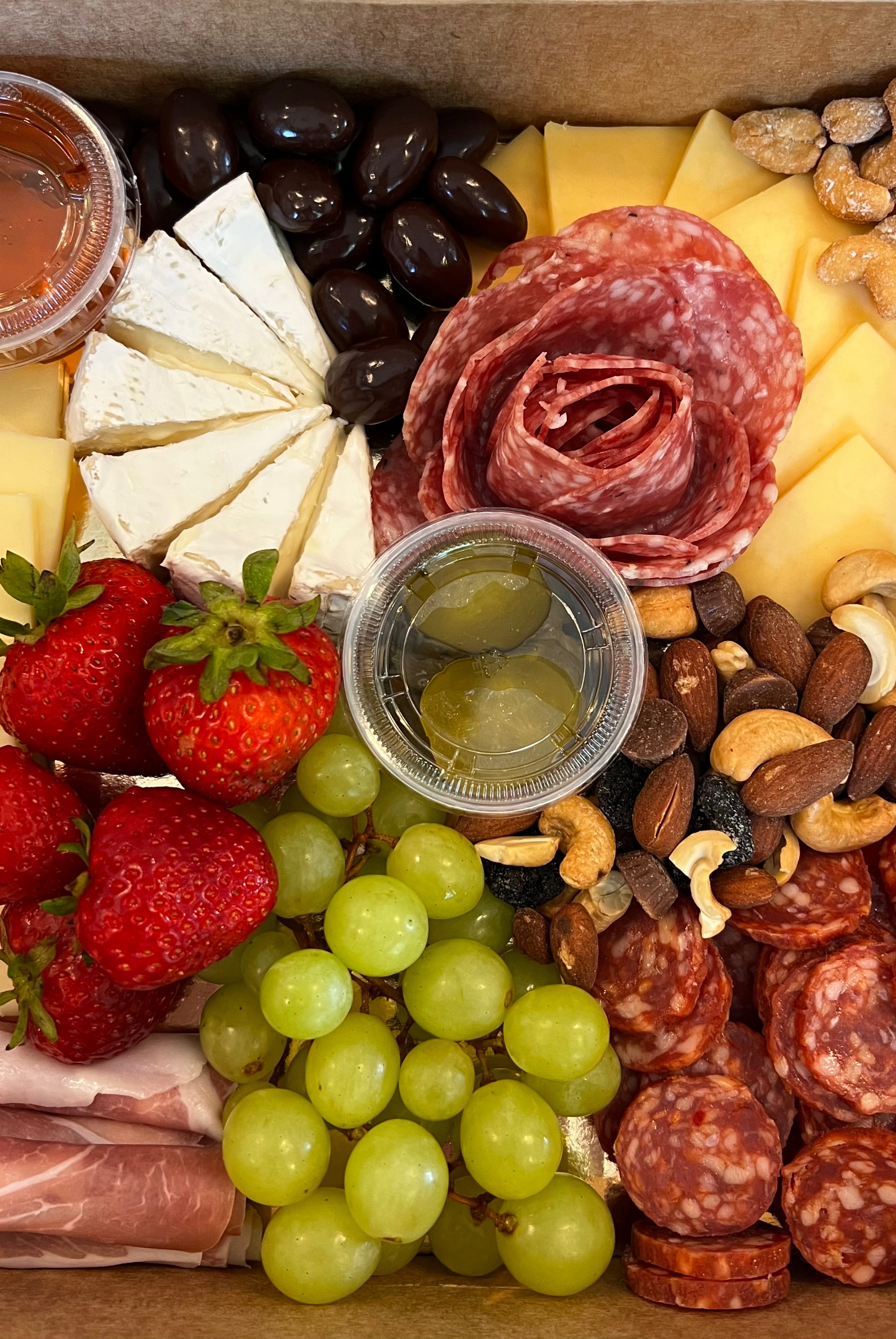 Charcuterie board prepared for delivery with cheese, nuts, meats and fruit