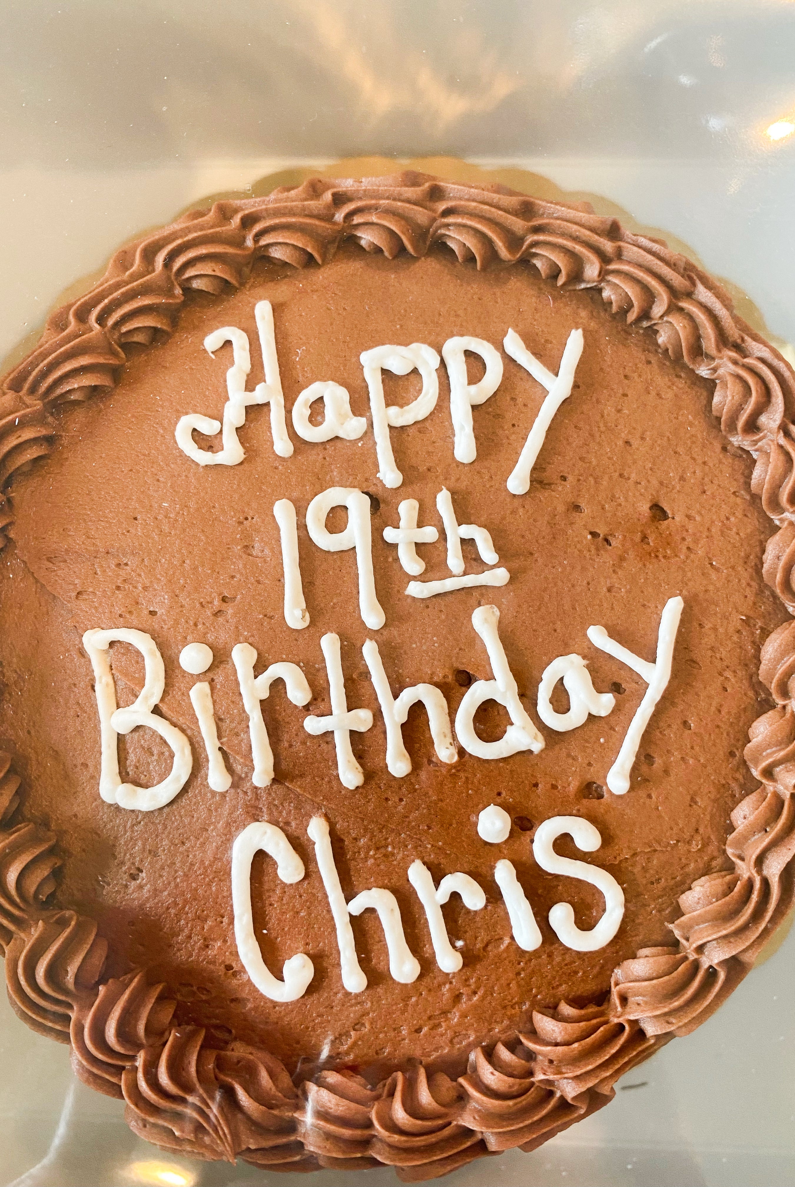 Cake with brown icing that says "happy 19th birthday Chris"