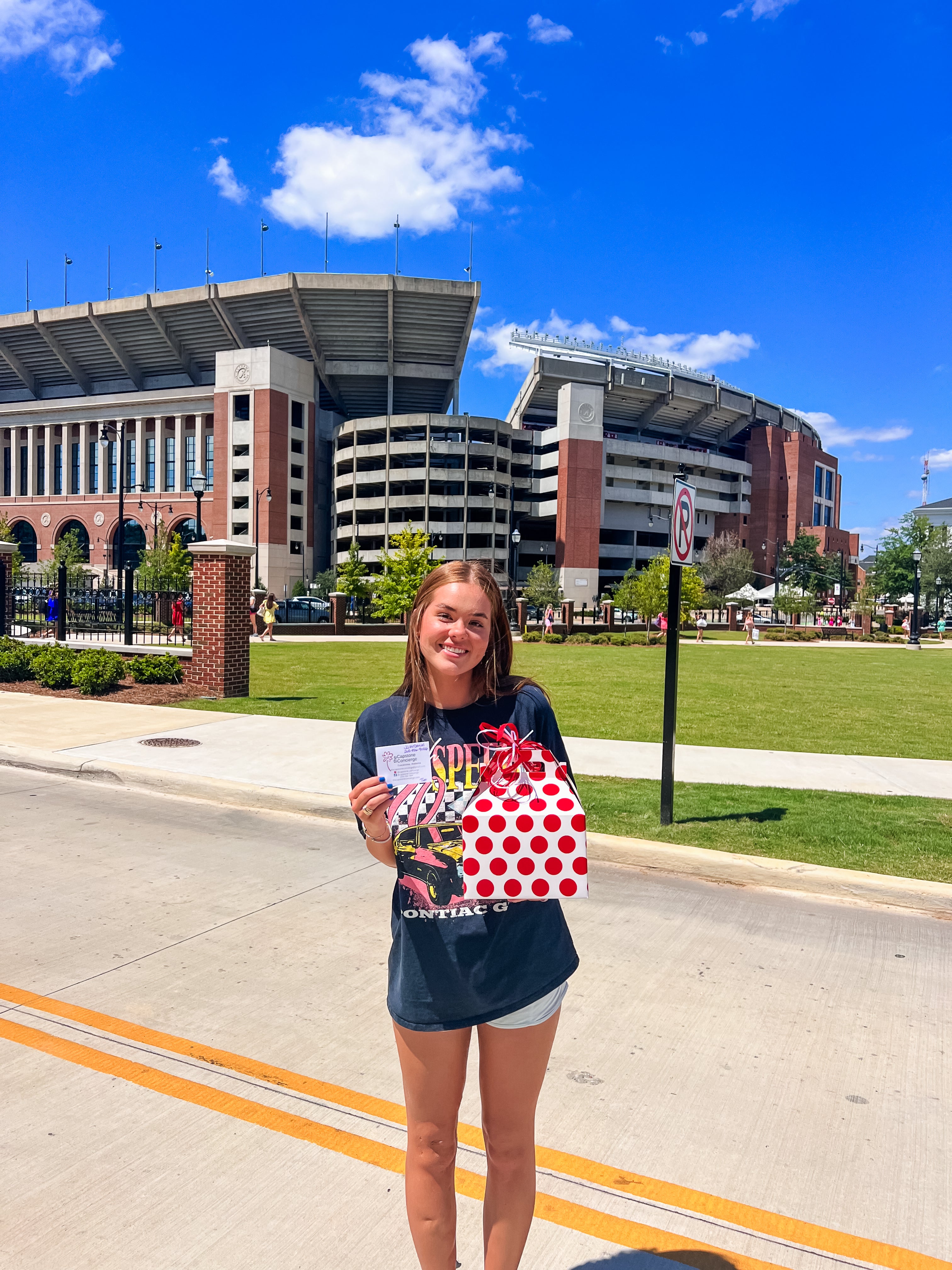 Girl holding red and white delivery outside of Bryant Denny stadium
